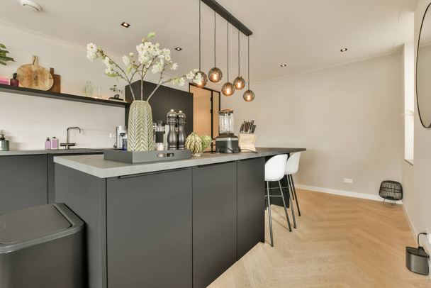 une cuisine moderne avec armoires noires et comptoirs blancs au centre de la pièce est un grand miroir sur le mur - Photo, image