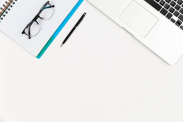 Notebook, occhiali, penna e laptop su uno sfondo bianco isolato, spazio di copia, vista dall'alto. - Foto, immagini