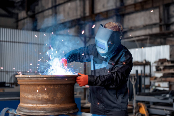 Electric wheel grinding on steel structure in factory. Man worker working with a metal product and welding it with a arc welding machine in a workshop. Industrial manufacturing. Welding metal part in a factory. Orange sparks. Copy space. - Photo, Image