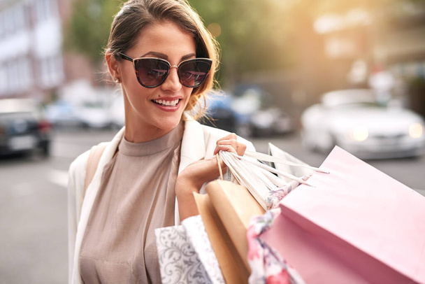 Fashion, shopping bag or rich girl in city or urban street for boutique retail sale or clothes discount deals. Sunglasses, financial freedom or trendy customer walking on road with luxury products. - Zdjęcie, obraz