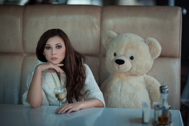 Sad κορίτσι στο τραπέζι με ένα παιχνίδι αρκούδα. - Φωτογραφία, εικόνα