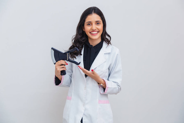Brazilian, Caucasian woman wearing lab coat, holding adipometer for body measurement, slimming. - Фото, изображение