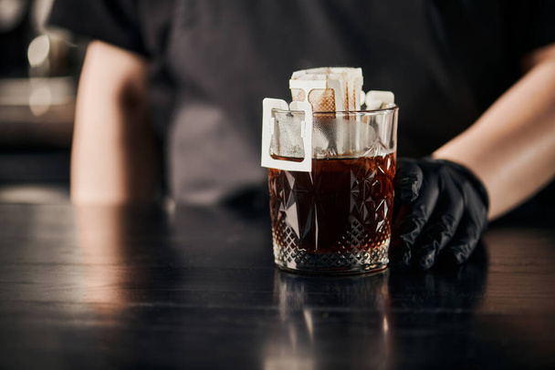 vágott kilátás barista főzés aromás kávé papírszűrő zsák és kristály üveg fekete asztalon - Fotó, kép