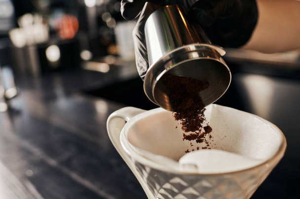 barista preparing V-60 style espresso, pouring fine grind coffee into ceramic dripper with filter - Photo, Image