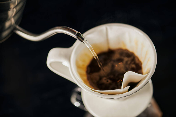 V-60 styl espresso vaření, vroucí voda nalévání do keramické kapátko s černou mletou kávou - Fotografie, Obrázek