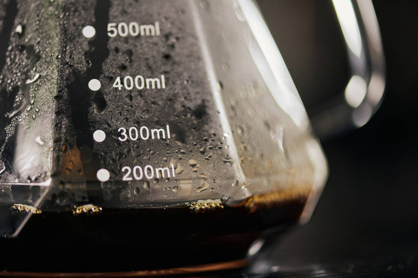 közeli kilátás a fekete frissen főzött eszpresszó üveg kávéskanna mérleg, csepegtető módszer - Fotó, kép