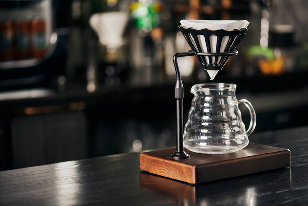 V-60 style method, dripper stand with filter bag above glass coffee pot on black wooden counter - Photo, Image