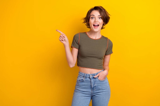 Photo of impressed astonished woman wear trendy t-shirt indicating at amazing proposition empty space isolated on yellow color background. - Foto, imagen