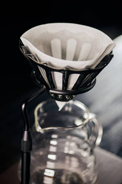 Kahve filtresinin kapalı görüntüsü damlatılmış olarak cam kahve demliğinin üzerinde duruyor, V-60 tarzı demleme yöntemi. - Fotoğraf, Görsel