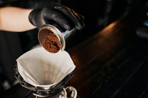 V-60 stijl espresso extractie, barista gieten koffie van jigger in filterzak op dripper stand - Foto, afbeelding