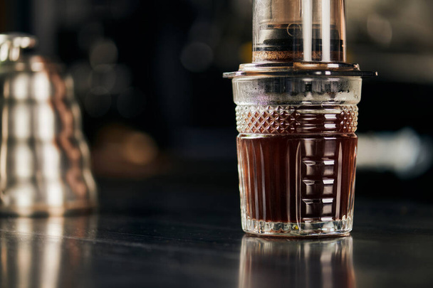 κρυστάλλινο ποτήρι με αρωματικό και φρεσκοψημένο espresso παρασκευασμένο σε καφετιέρα aero press  - Φωτογραφία, εικόνα