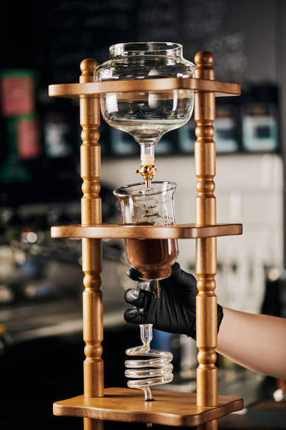 barista en guante negro ensamblando cafetera de goteo frío con café molido, cerveza espresso alternativa - Foto, imagen