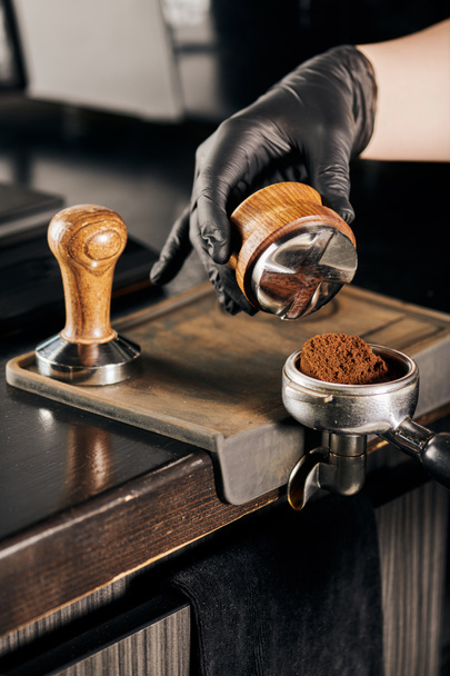 cropped view of barista holding tamper and portafilter with aromatic coffee in coffee shop - Photo, Image