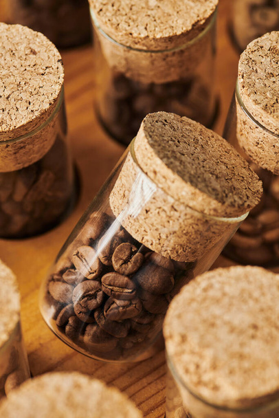 granos de café en frascos de vidrio con corcho, tostado, cafeína y energía, fondo de café, macro  - Foto, Imagen