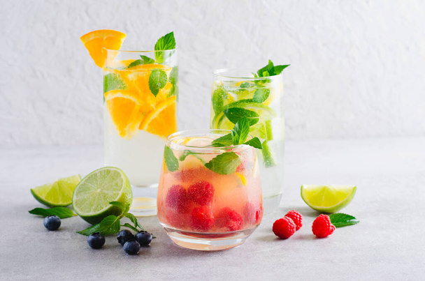 Letnie napoje, owoce, owoce cytrusowe i jagody orzeźwiające cytryny lub koktajle na jasnym tle - Zdjęcie, obraz