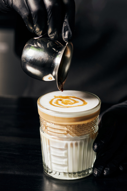 Barista bereitet Latte Macchiato zu, gießt Espresso in Glas, Kanne mit Kaffee, Milchschaum  - Foto, Bild