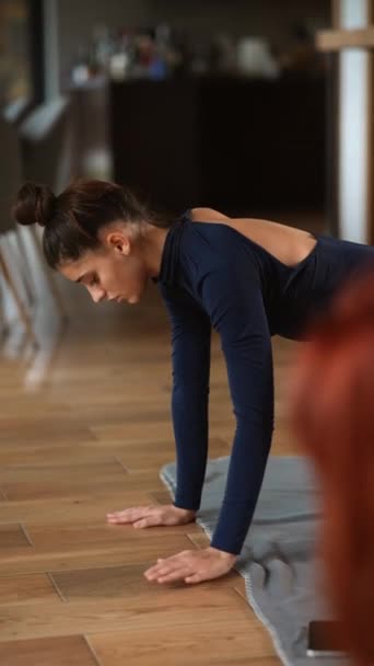 Due belle ragazze stanno facendo esercizi di yoga a casa stretching corpo concentrato sulla pratica. Giovani, interni e stile di vita sano. - Filmati, video