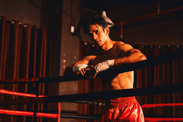 Exhausted after intense Muay Thai training session or fight, Asian boxer leaning against the ring. Rest and recover, embracing the peacefulness after workout. Impetus - Foto, afbeelding