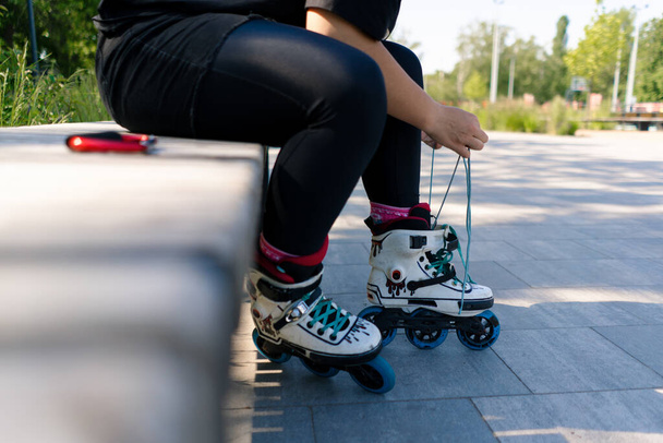 jovem hipster menina vestindo patins amarrando atacadores no parque de skate antes de patinar rua esporte extremo closeup de pernas - Foto, Imagem