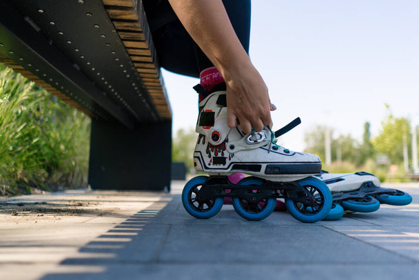 fiatal hipster lány felvesz görkorcsolya korcsolya park megkezdése előtt korcsolyázás utca extrém sport közelkép lábak - Fotó, kép