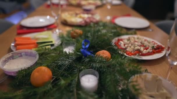 Yakın çekimde, arkadaşlarının yemek masasını lezzetli yemeklerle kutluyorlar. Noel 'de parti masasında yemek ve içecek konsepti 4K görüntüler. Yüksek kalite 4K görüntü. Yavaş çekim - Video, Çekim