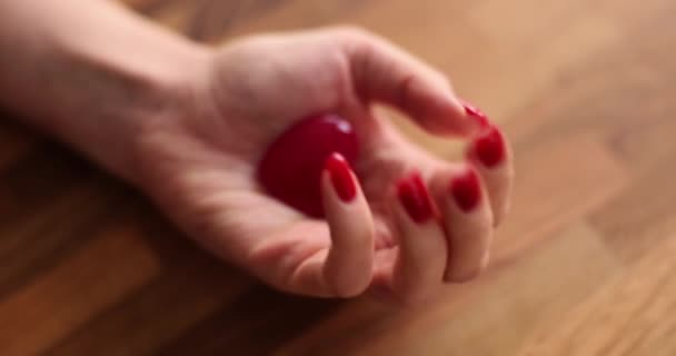 Vrouwelijke hand met rode nagels toont kleine hart speelgoed figuur. Symbool van liefde op sierlijke vrouwelijke palm op houten oppervlak. Zorg en ondersteuning slow motion - Video