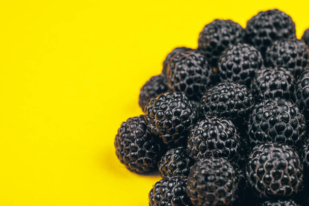 Heap of fresh ripe and sweet raspberries on yellow background. Black raspberries. Macro shot. - Valokuva, kuva