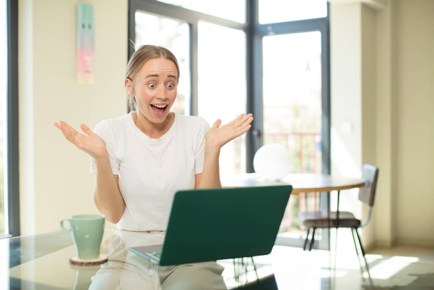 caucasian pretty woman with a laptop feeling happy, excited, surprised or shocked, smiling and astonished at something unbelievable - Foto, Bild
