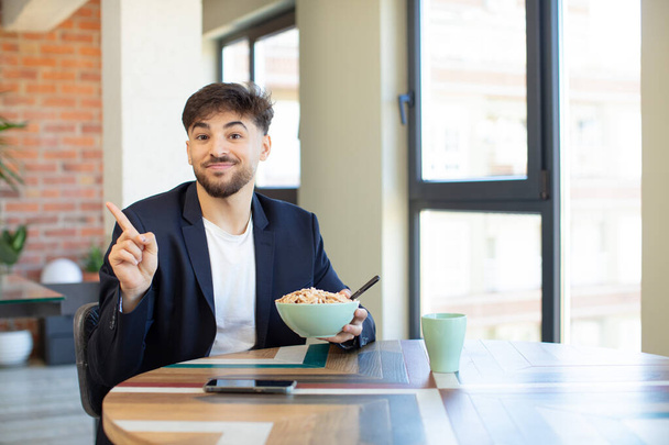 young handsome man smiling cheerfully, feeling happy and pointing to the side. breakfast concept - 写真・画像