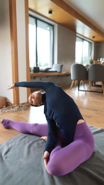 Two Beautiful girls are doing yoga exercises at home stretching bodies concentrated on practice. Young people, interiors and healthy lifestyle concept. - Footage, Video
