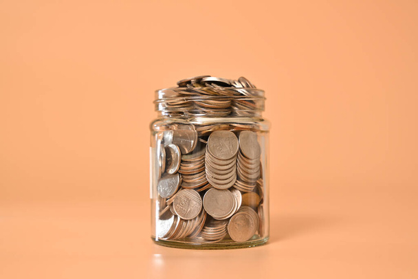 Glasgefäß mit Münzen auf abstraktem Hintergrund, Investitionen in Finanzunternehmen, Wachsendes Geld, Menschen sparen Geld, Geldsparen und Finanzbanking. Hochwertiges Foto - Foto, Bild