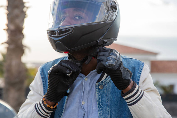 A motorcyclist tightens his helmet belt before driving his motorcycle - Foto, immagini