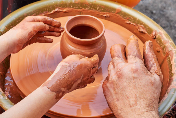 Insegnare a un bambino a fare ceramiche con argilla rossa. Argilla mani di ceramica da vicino lavorando su artigianato ruota. Creazione di stoviglie in argilla. Lavorazione con argilla rossa.  - Foto, immagini