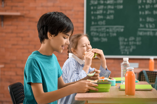 Kleine Schüler essen im Klassenzimmer zu Mittag - Foto, Bild