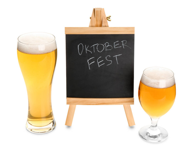 Bril koud bier en krijtbord met woord OKTOBERFEST op witte ondergrond - Foto, afbeelding
