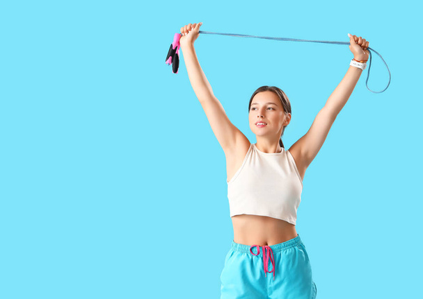 Sportieve jonge vrouw met springtouw op blauwe achtergrond - Foto, afbeelding