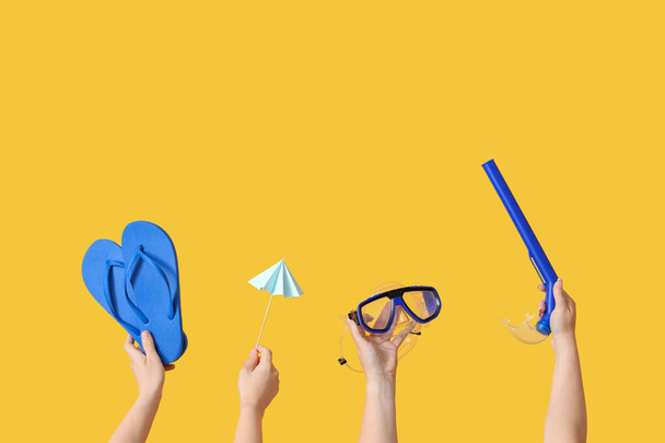 Many hands holding beach accessories on yellow background - Fotoğraf, Görsel