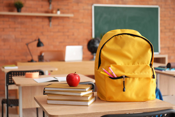 Sırt çantasında taze elma ve sınıfta masanın üstünde kitaplar var. - Fotoğraf, Görsel