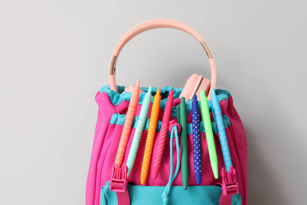 Gri arka planda farklı kırtasiye malzemesi olan renkli okul çantası - Fotoğraf, Görsel