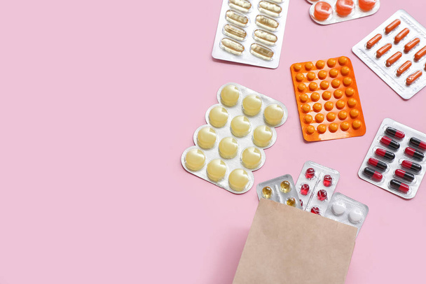 Bolsa de compras con diferentes píldoras en blisters sobre fondo rosa - Foto, Imagen