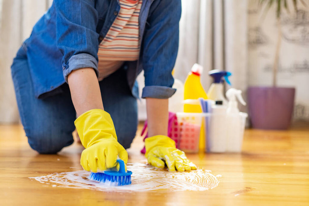 Woman in rubber gloves is using floor brush to cleaning floor. Housekeeping and cleaning concept. - Foto, Bild