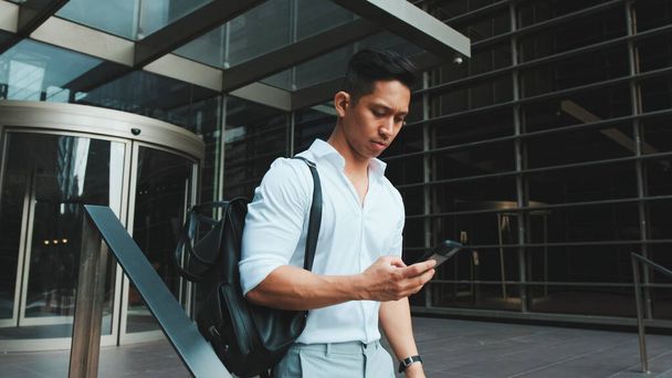 Young businessman leaving the business center with smartphone - Photo, image