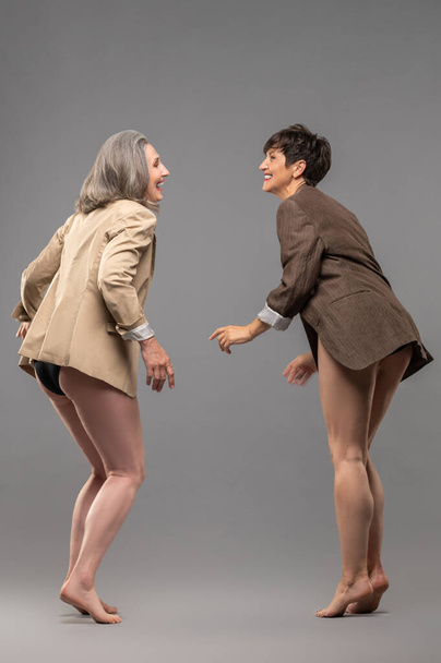 Young spirit. Two senior women in panties and jackets dancing and feeling excited - Photo, Image