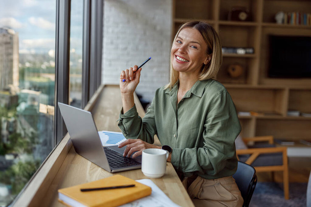 Responsabile vendite donna seduto in coworking moderno e lavorare sul computer portatile. Foto di alta qualità - Foto, immagini