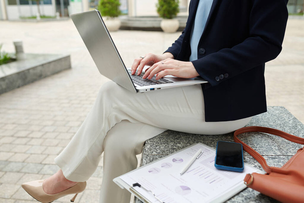 Cropped image of elegant financial adviser working on laptop outdoors - Foto, afbeelding