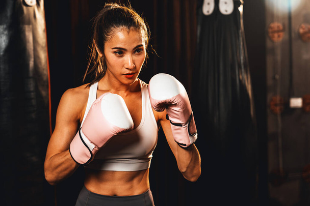 Female muay thai boxer in defensive guard stance wearing glove in the gym ready to fight posing, boxing training and professional martial art sport. Impetus - Photo, Image