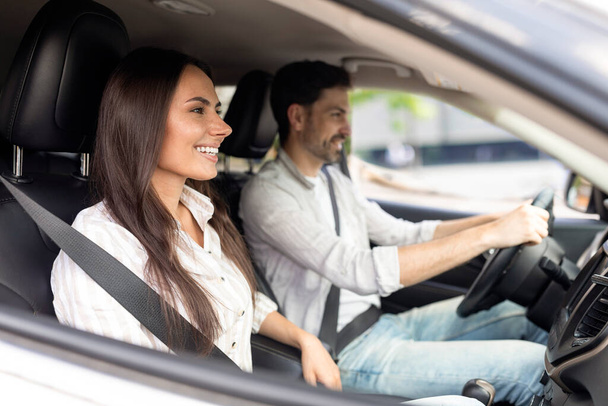 Car renting, leasing, buying. Cheerful positive loving millennial couple test drive new auto together, shot from side window. Happy man and woman have car trip in summer. Vacation, recreation - Φωτογραφία, εικόνα