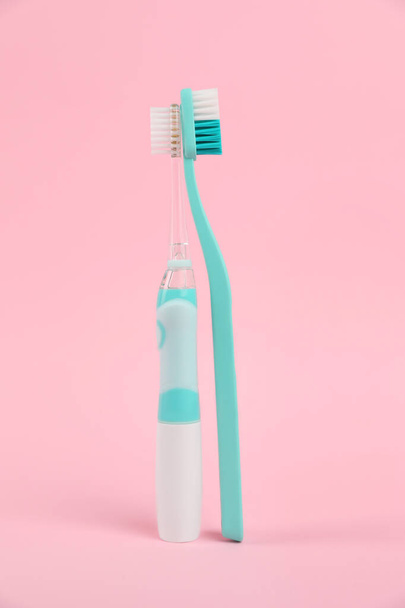 Elektrische en plastic tandenborstels op een roze achtergrond. Tandheelkundige verzorging - Foto, afbeelding