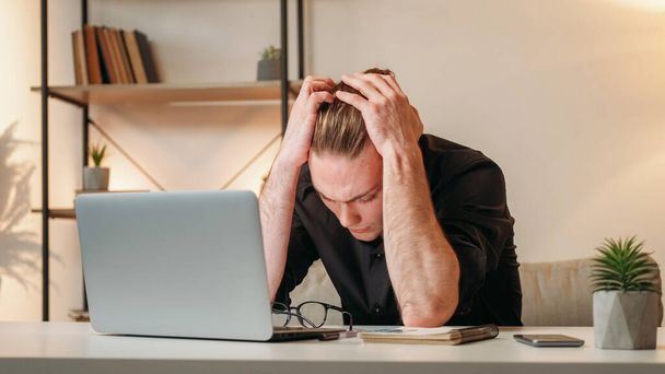Professional fatigue. Tired employee. Exhausted business man suffering from headache clutching head at home office workplace interior with free space. - Foto, Imagen