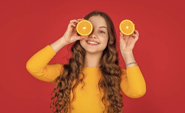 teen dítě úsměv držet oranžové ovoce na fialovém pozadí. - Fotografie, Obrázek